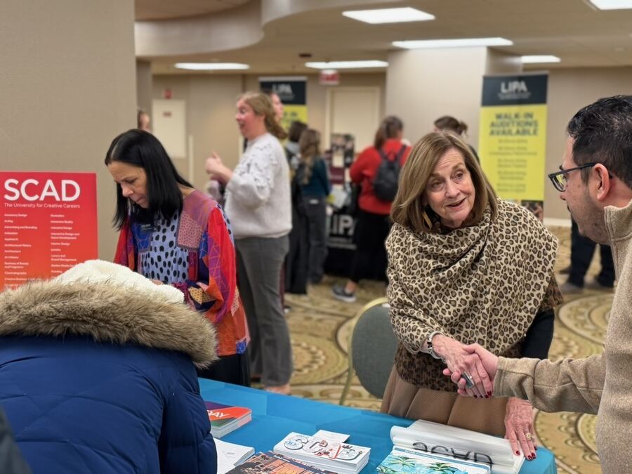 A representative greeting visitors near the SCAD table